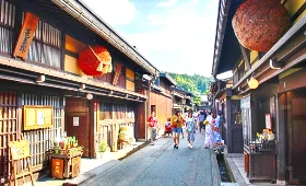 A street with buildings and people walkingDescription automatically generated